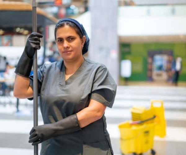 Portrait of a Latin American cleaning lady mopping the floor while working at a shopping mall and looking at the camera smiling